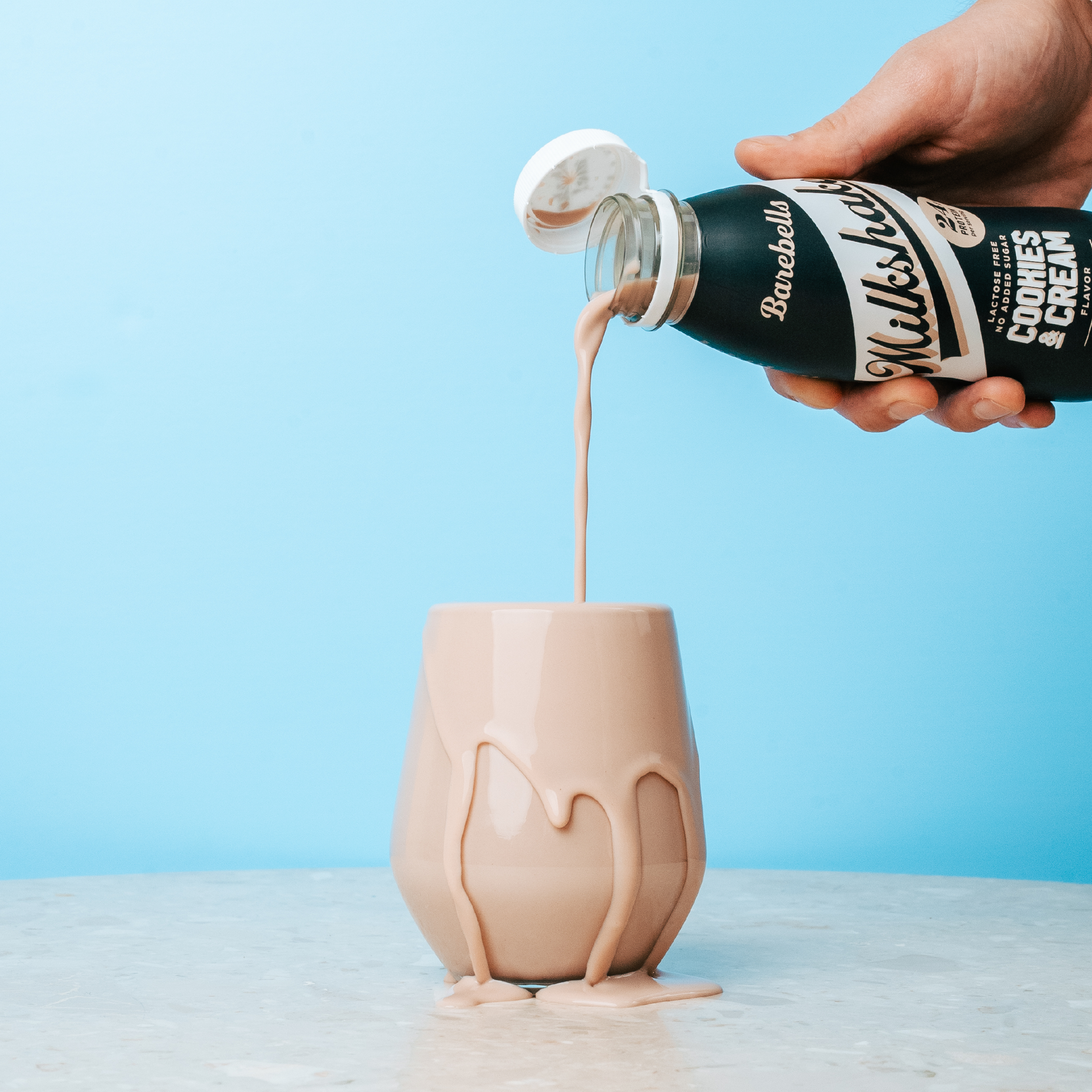 Barebells Milkshake Cookies & Cream eiwitshake wordt in een glas geschonken - sfeerfoto